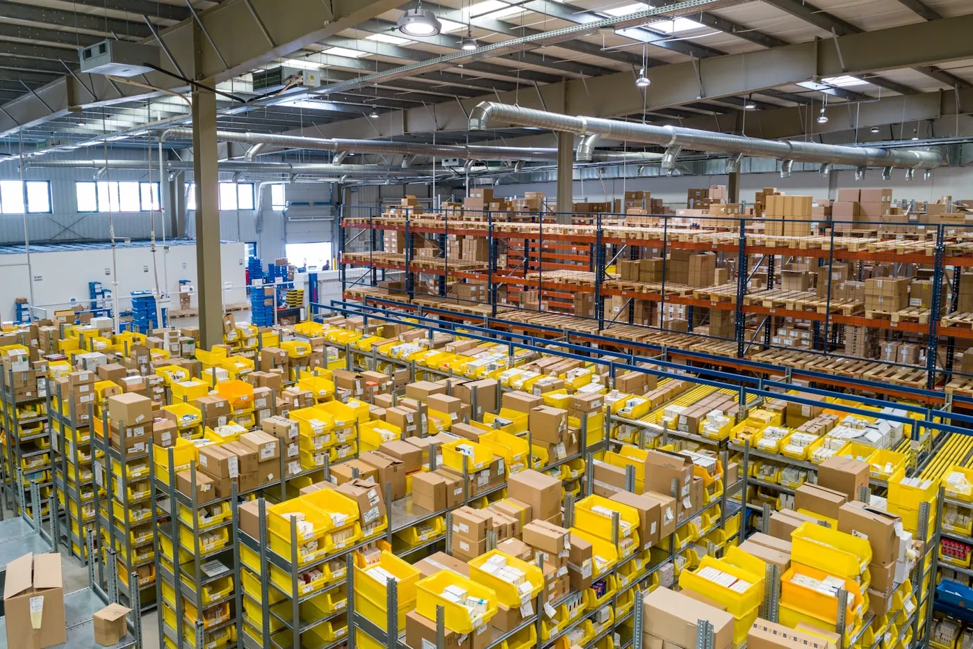 Organised B2B logistics warehouse with high-bay racking and yellow picking bins